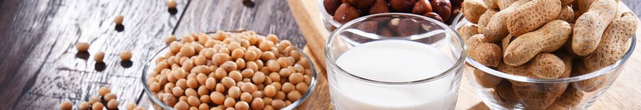 Allergenen: Een glas melk en bakjes met diverse noten op tafel